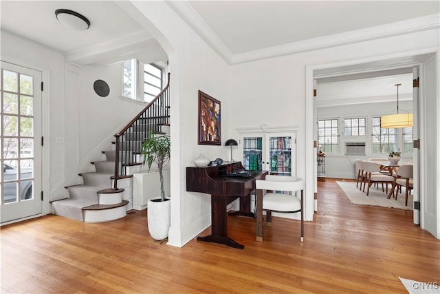 entryway featuring plenty of natural light, ornamental molding, stairs, and wood finished floors