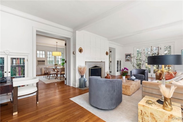 living room with a fireplace, crown molding, beamed ceiling, and wood finished floors