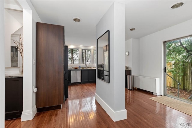 hall featuring a sink, baseboards, plenty of natural light, and dark wood finished floors