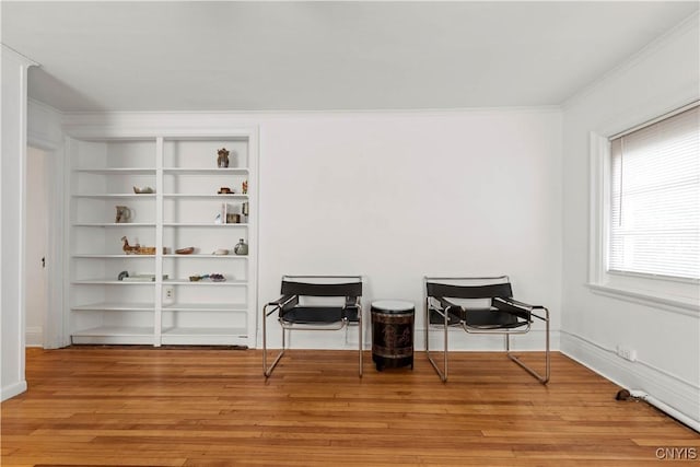 living area with baseboards, light wood-style flooring, and crown molding