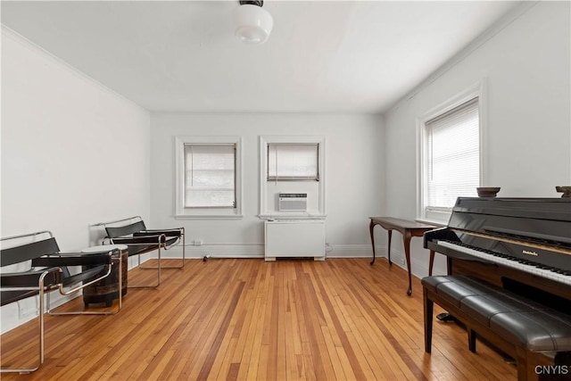 living area featuring radiator, light wood-style floors, baseboards, and cooling unit