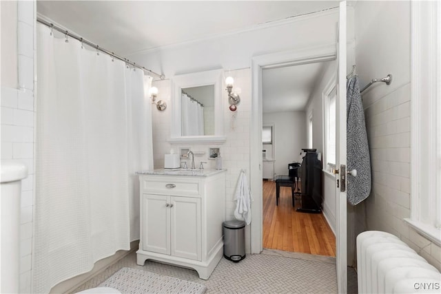 full bath with a shower with curtain, radiator, vanity, and tile patterned flooring