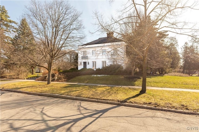 view of front facade with a chimney and a front yard