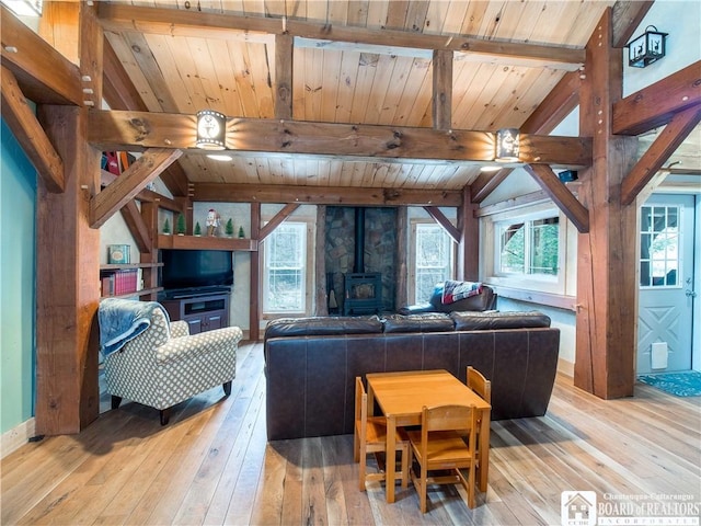 living room with a wealth of natural light, beamed ceiling, and a wood stove