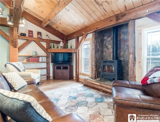 living area with wooden ceiling, a wood stove, wood finished floors, and lofted ceiling with beams