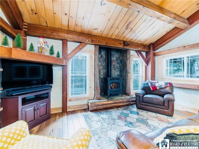 living area with lofted ceiling with beams, wood ceiling, a wood stove, and wood finished floors