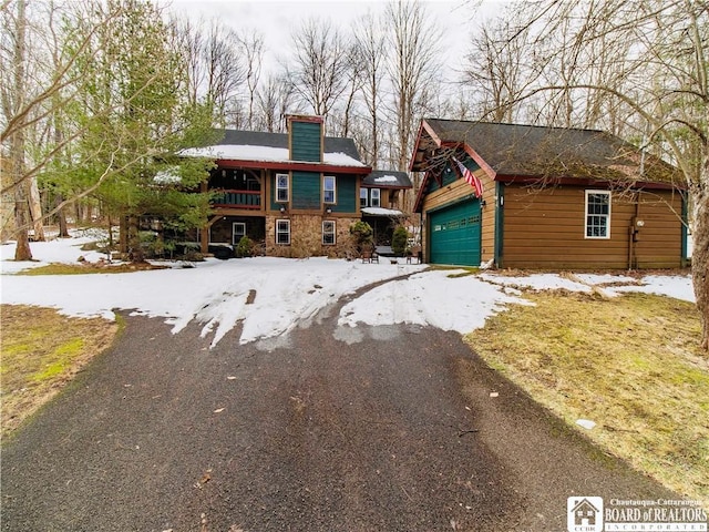 view of front facade featuring a garage, stone siding, and aphalt driveway