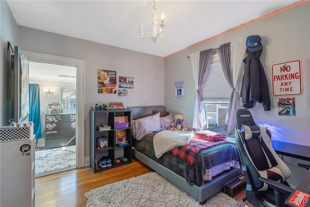 bedroom featuring an inviting chandelier and wood finished floors