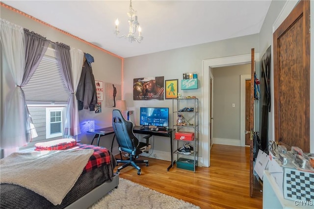 bedroom featuring baseboards, a notable chandelier, and wood finished floors