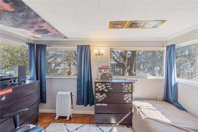 bedroom with radiator heating unit, wood finished floors, and baseboards