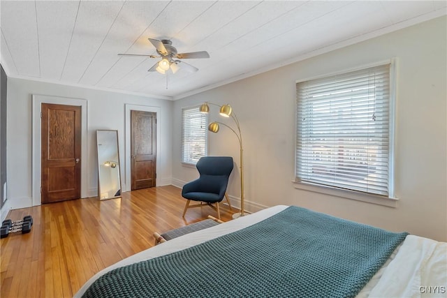 bedroom featuring ceiling fan, wood finished floors, baseboards, and ornamental molding