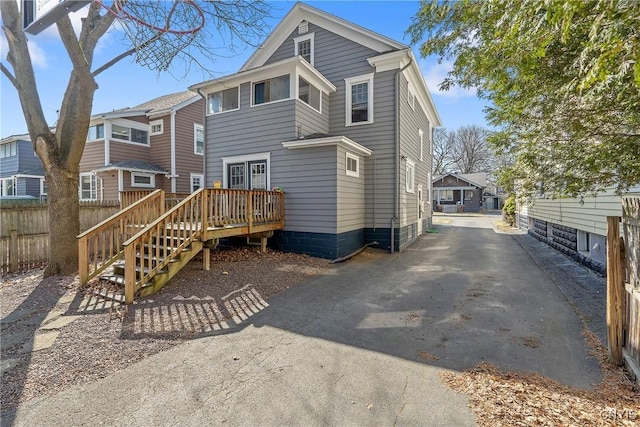 back of house with aphalt driveway, a wooden deck, and fence