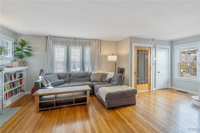 living room featuring visible vents, baseboards, and light wood finished floors