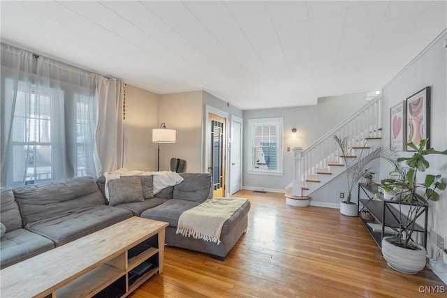 living area featuring stairs, light wood-style floors, and a wealth of natural light