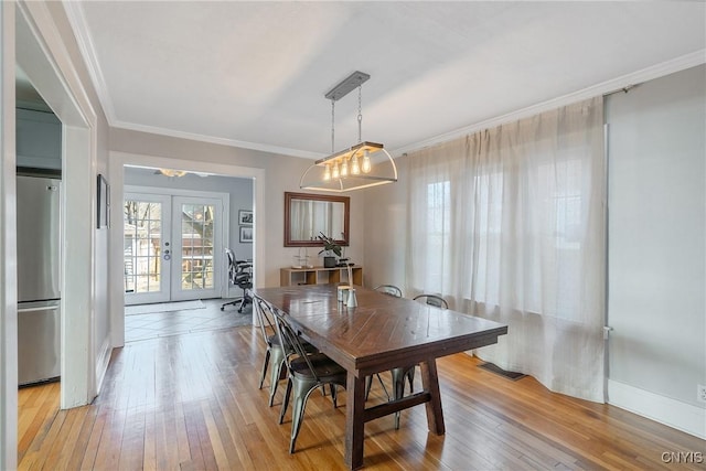 dining room with light wood-type flooring, french doors, baseboards, and crown molding