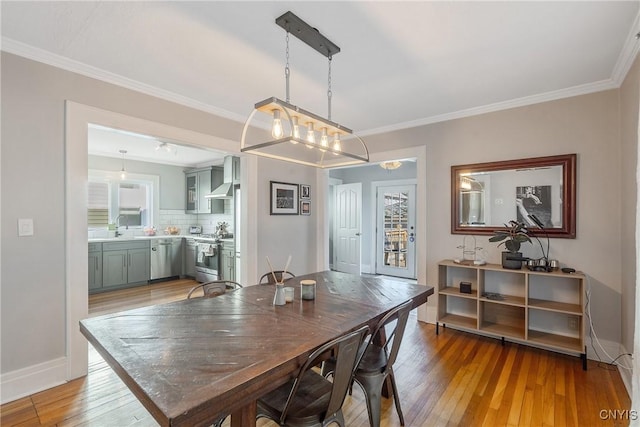 dining room with crown molding, baseboards, and light wood-type flooring