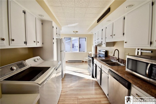 kitchen with light wood finished floors, a baseboard radiator, separate washer and dryer, stainless steel appliances, and a sink