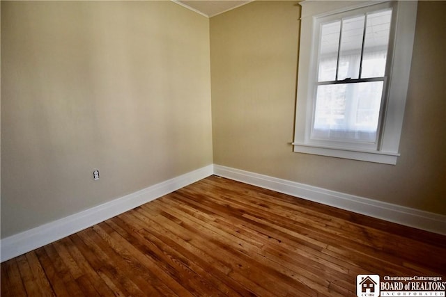 spare room featuring baseboards and wood-type flooring