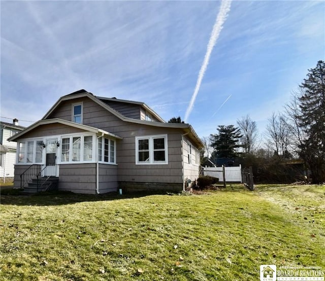 rear view of house with a lawn and fence