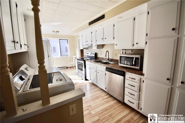 kitchen with a sink, a baseboard heating unit, stainless steel appliances, white cabinets, and light wood finished floors