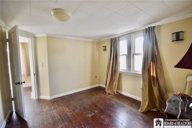 spare room with baseboards, dark wood finished floors, and crown molding