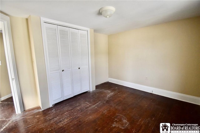 unfurnished bedroom featuring hardwood / wood-style floors, baseboards, and a closet