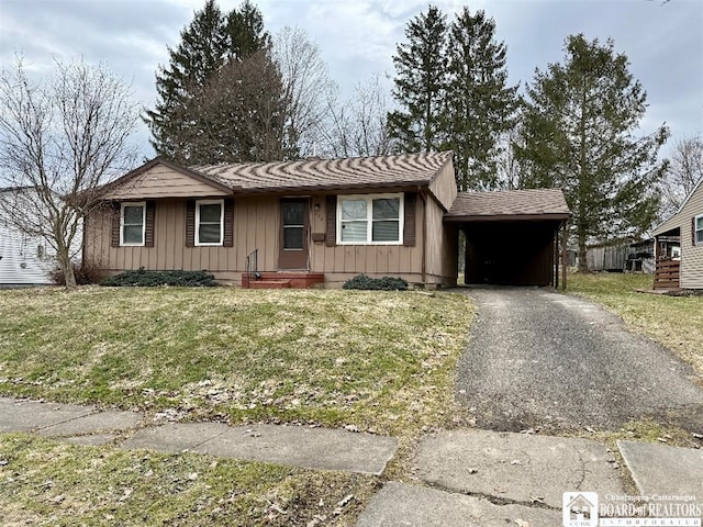 single story home featuring an attached carport, a shingled roof, a front lawn, aphalt driveway, and board and batten siding