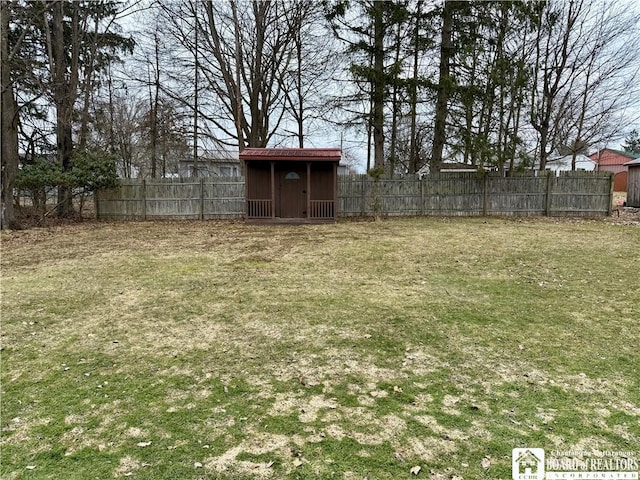 view of yard with an outbuilding, a fenced backyard, and a shed