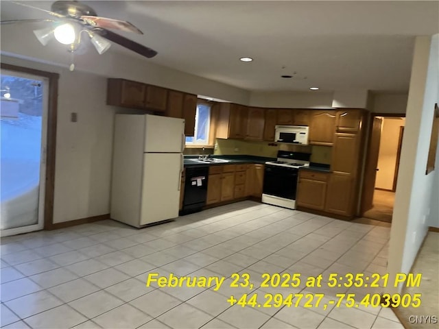 kitchen with dark countertops, recessed lighting, white appliances, light tile patterned flooring, and baseboards