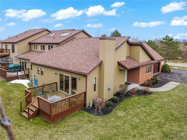 back of property featuring a lawn, a chimney, a deck, and a shingled roof