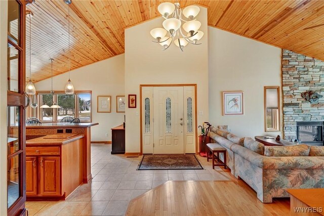 foyer with high vaulted ceiling, light tile patterned flooring, a fireplace, wooden ceiling, and a chandelier