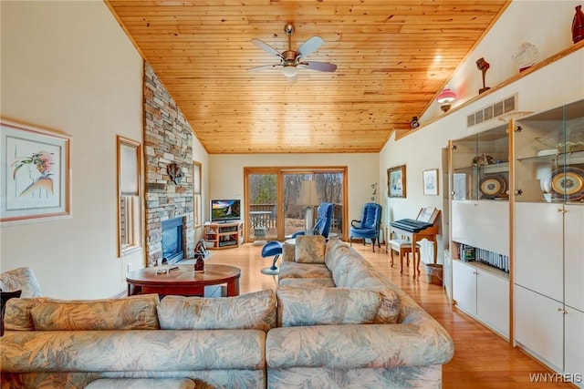 living area featuring light wood-type flooring, visible vents, a stone fireplace, and wooden ceiling