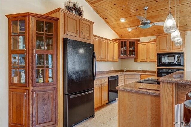 kitchen featuring glass insert cabinets, decorative light fixtures, light tile patterned floors, dark stone countertops, and black appliances