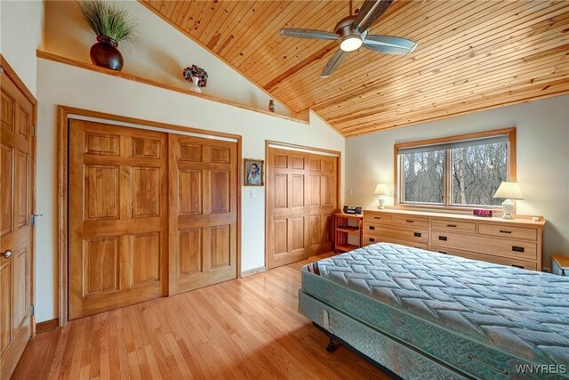 bedroom featuring ceiling fan, vaulted ceiling, wood ceiling, light wood-style floors, and multiple closets