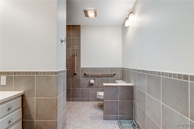 bathroom featuring a wainscoted wall, toilet, tile walls, and vanity