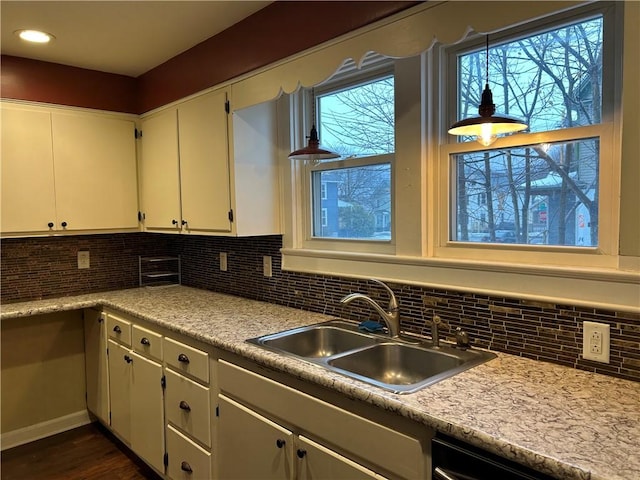 kitchen featuring backsplash, dishwasher, white cabinets, and a sink