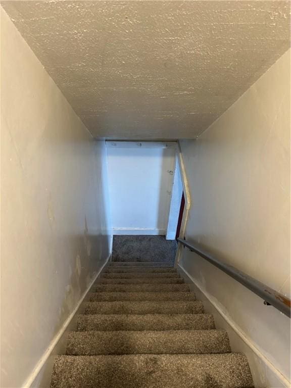 stairway with carpet flooring and a textured ceiling