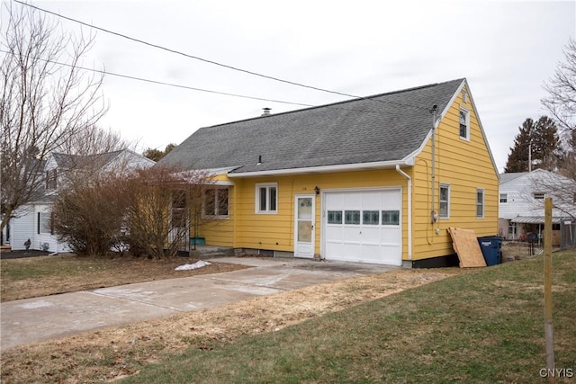 view of front of house featuring a front yard, a garage, driveway, and a shingled roof