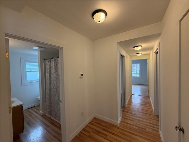 hallway with light wood-style flooring and baseboards