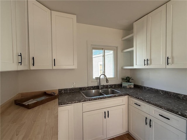 kitchen featuring open shelves, white cabinets, and a sink