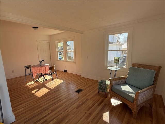 sitting room with visible vents, crown molding, baseboards, and wood finished floors