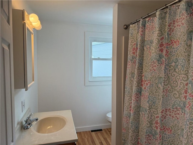 full bath with a shower with curtain, toilet, wood finished floors, baseboards, and vanity