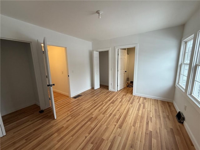 unfurnished bedroom featuring visible vents, baseboards, and light wood-style floors