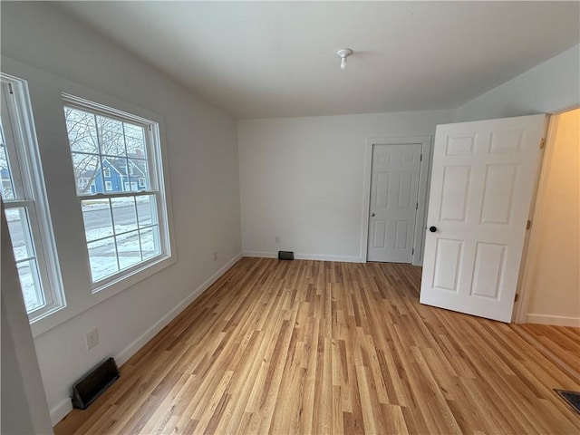 empty room featuring visible vents, baseboards, and light wood-type flooring