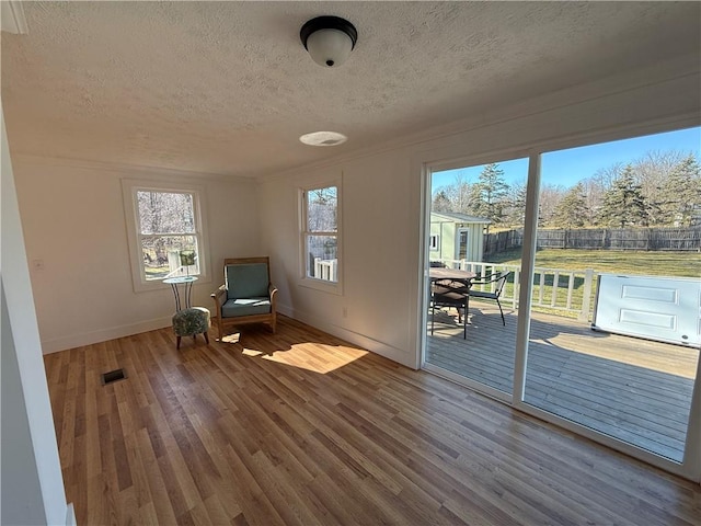 unfurnished room featuring visible vents, wood finished floors, baseboards, and a textured ceiling