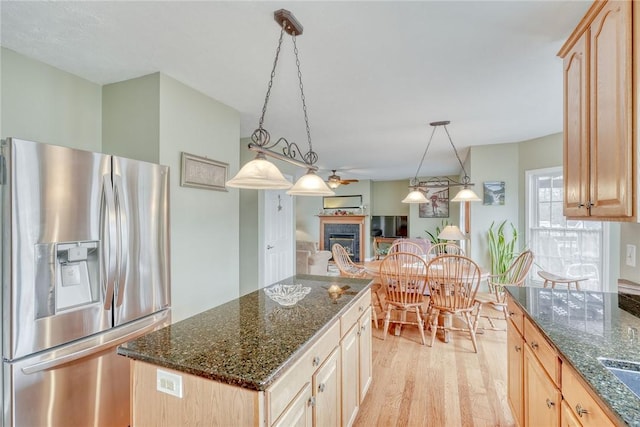 kitchen featuring light brown cabinetry, a fireplace, stainless steel fridge with ice dispenser, and light wood finished floors