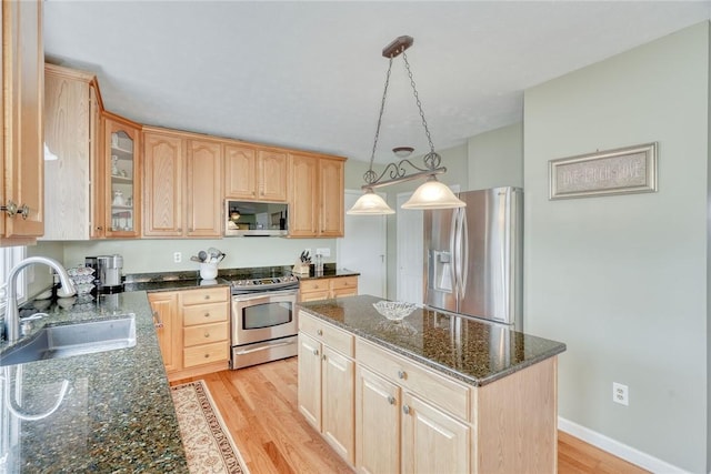 kitchen with a sink, stainless steel appliances, light wood-type flooring, and light brown cabinets