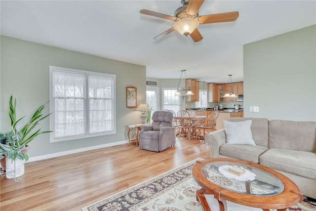 living room featuring light wood finished floors, ceiling fan, and baseboards