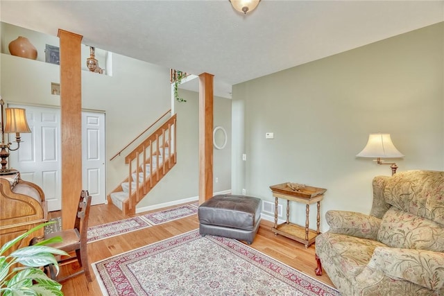 living room with visible vents, stairs, decorative columns, and wood finished floors