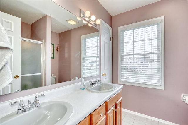 bathroom with double vanity, baseboards, a stall shower, and a sink